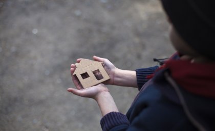 person holding a small cardboard house