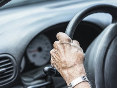 older hands on steering wheel