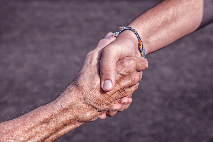 young hand shaking older hand