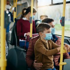 man and son riding on bus with masks 