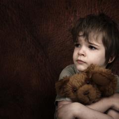 child holding toy bear looking sad
