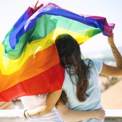 women hugging holding a rainbow flag