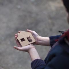 Person holding a small cardboard house  in their hands