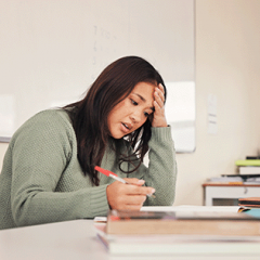 Female teacher grading tests looking stressed