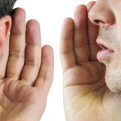 man whispering in other man's ear