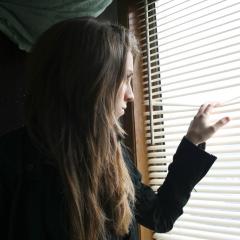 woman peering through blinds 