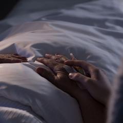 hand comforting person in a hospital bed 