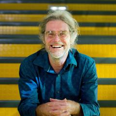 Professor Darryl Eyles smiling, sitting on a staircase